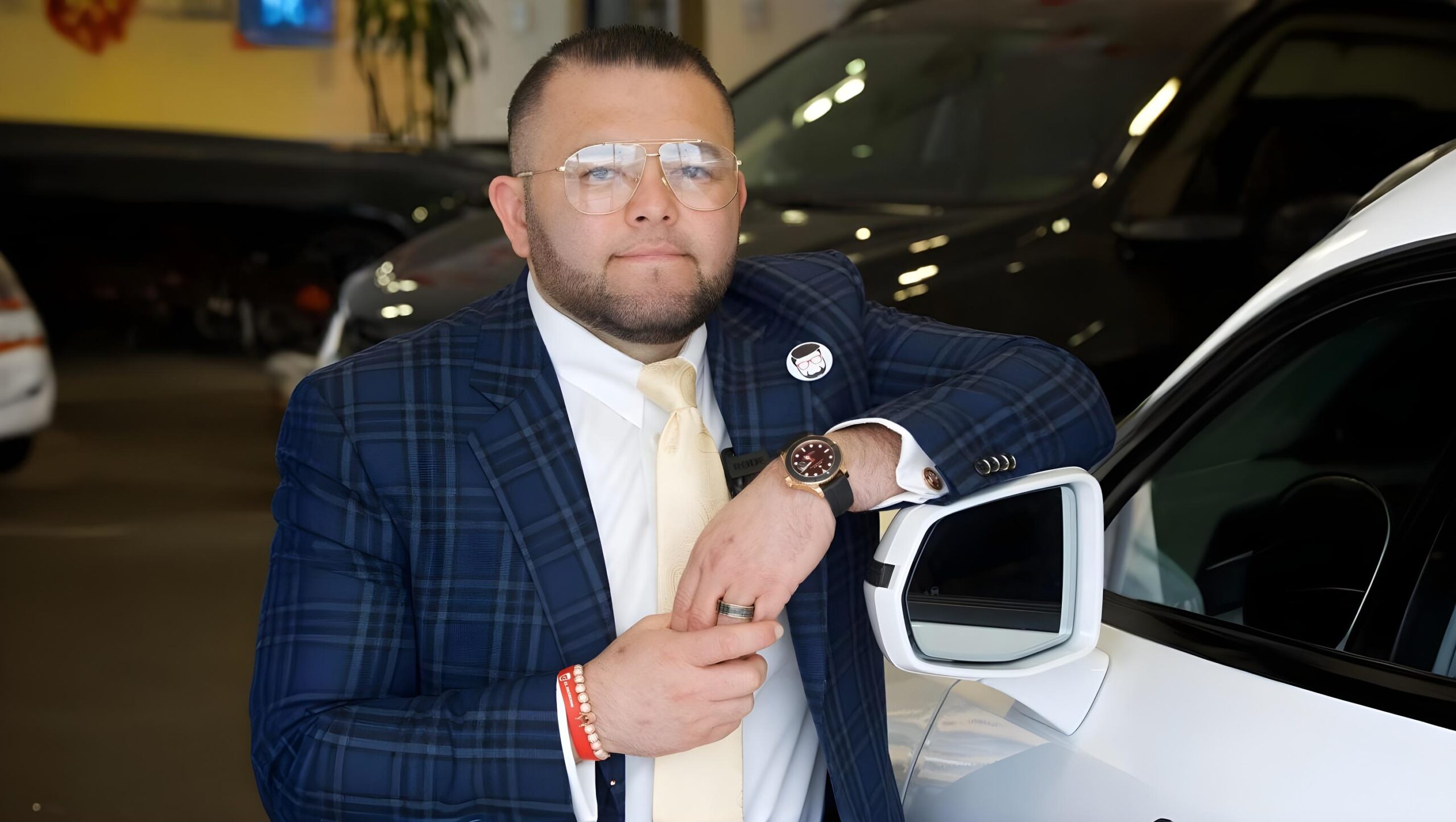 EL Patronn beside a luxury car